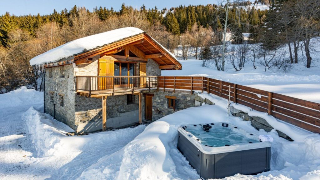 Mountain chalet with outdoor hot tub surrounded by snow